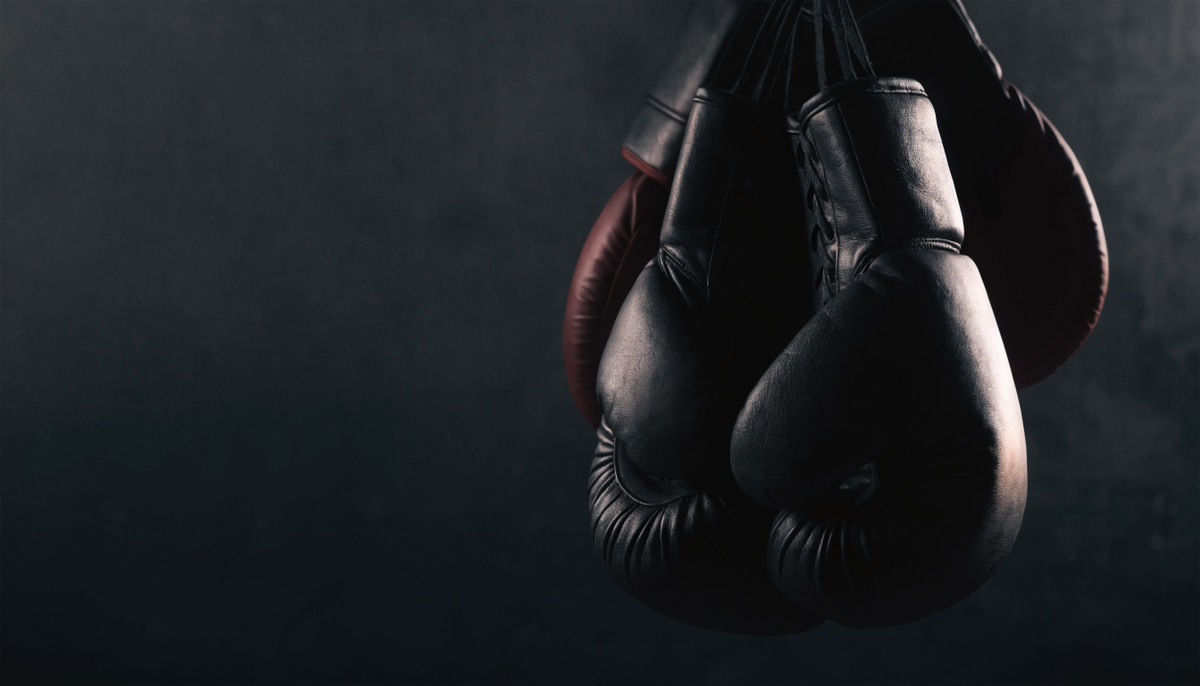 Leather boxing gloves hanging in a dark gym