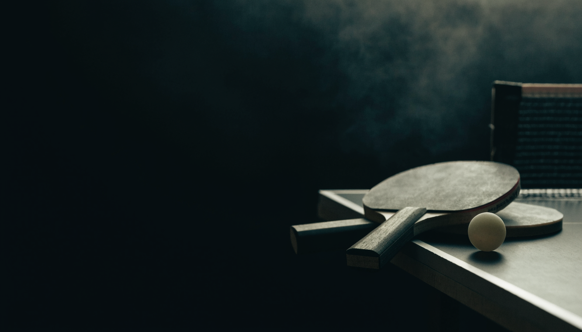 Table tennis paddles and ball on a dark table